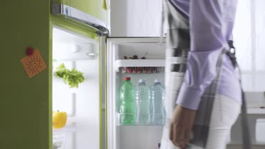 Genç kadın mutfakta yemek hazırlama buzdolabı, sağlıklı yaşam ve beslenme kavramı üzerinden taze sebze alıyor