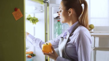 Buzdolabından taze sağlıklı sebze almak ve öğle yemekleri, diyet ve yaşam tarzı konsept hazırlama genç kadın
