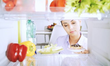 Sağlıklı sebze ve bir tatlı tutan kararsız kadın o ne yemek seçme ve gıda, sağlıklı yaşam tarzı ve diyet kavramı karşılaştırma