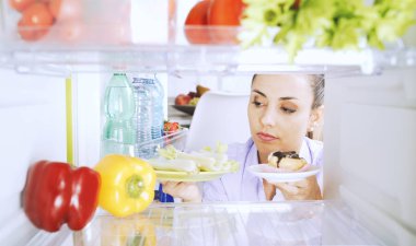 Sağlıklı sebze ve bir tatlı tutan kararsız kadın o ne yemek seçme ve gıda, sağlıklı yaşam tarzı ve diyet kavramı karşılaştırma