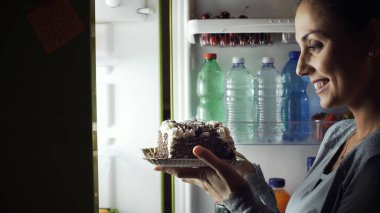 Geceleri uyanma ve buzdolabı, diyet ve yaşam tarzı konseptinden sağlıksız bir aperatif almak aç gözlü kadın