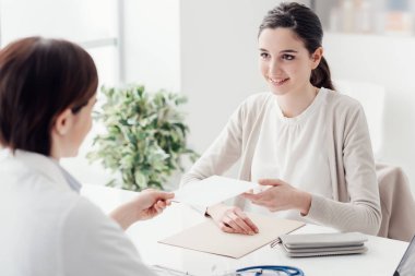 Doktorun muayenehanesindeki hasta gülümsüyor ve reçete, sağlık ve tedavi konsepti alıyor.