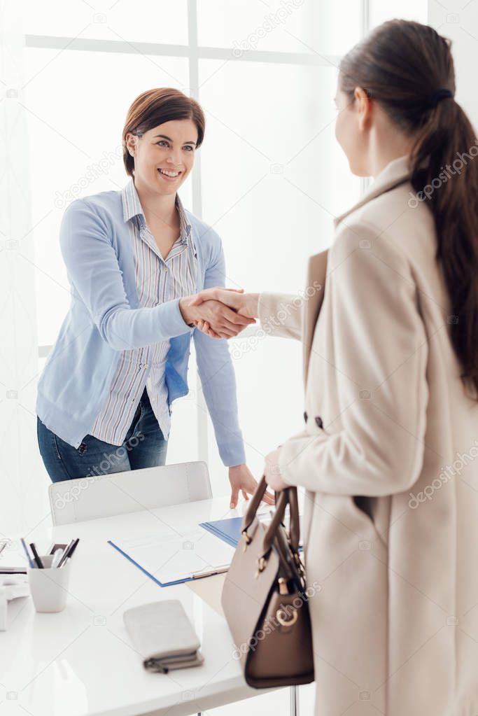 Business meeting in the office, a businesswoman is giving an handshake to the customer; job interview and agreement concept