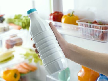 Bir şişe buzdolabı, beslenme ve diyet konseptinden taze süt alarak kadın