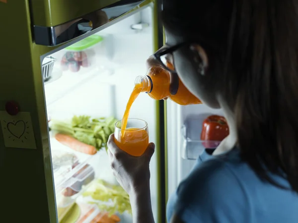 Mulher Tomando Uma Garrafa Suco Laranja Fresco Geladeira Derramando Copo — Fotografia de Stock