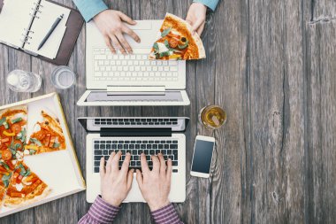 Ofis masasında çalışan iş adamları ve lezzetli bir pizzayla öğle yemeği arası veriyorlar.