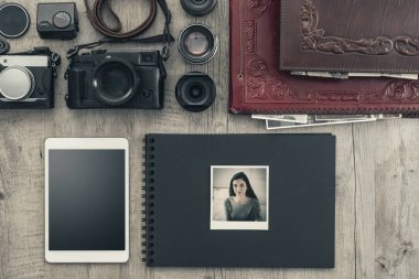 Klasik bir masaüstü, teknoloji ve yaratıcılık kavramında fotoğraf ekipmanları, kameralar, fotoğraf albümü ve dijital tablet