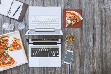 Ofis büro dizüstü bilgisayarlar ve pizza bir kutusunda, öğle yemeği molası kavramı ile