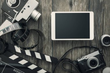 Klasik film kamerası, tablet, alkış tahtası, film şeridi ve masaüstündeki eski kamera, sinema ve video yapımı konsepti