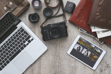 Kaliteli ahşap bir masaüstünde dizüstü bilgisayarı ve dijital tableti olan hippi fotoğraf ekipmanları düz yerde.