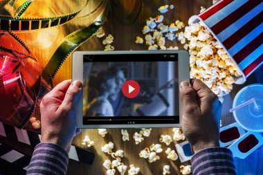 Bir dijital holding eller dokunmatik ekran tablet patlamış mısır, 3d gözlük ve film şeridi ile; film online akış sinema ve eğlence kavramı