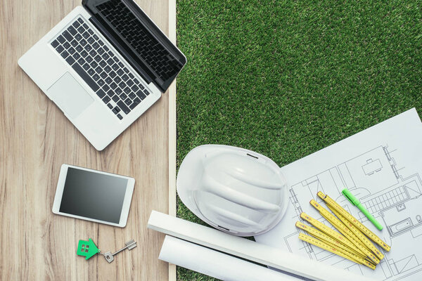 Energy efficient house design and construction, desktop with house project, folding meter, laptop and safety helmet