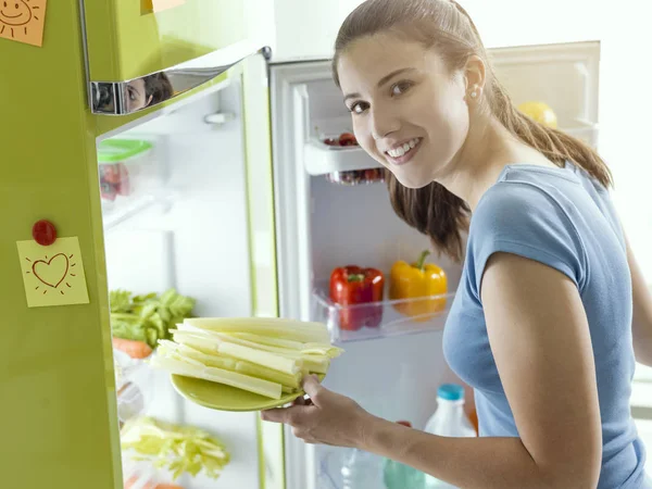 Mulher tomando aipo fresco da geladeira — Fotografia de Stock