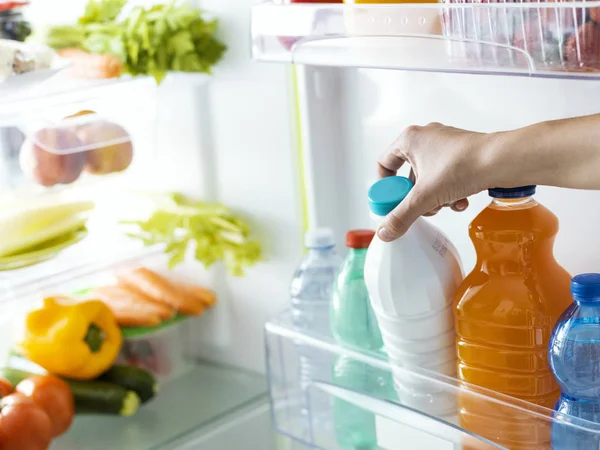 Mujer tomando una botella de leche de la nevera — Foto de Stock