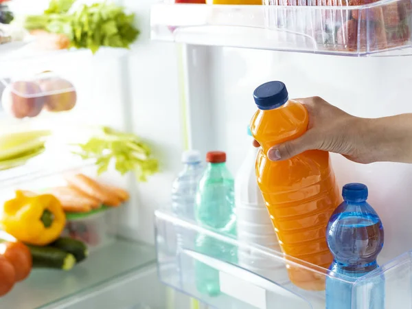 Mujer tomando una botella de jugo de naranja — Foto de Stock