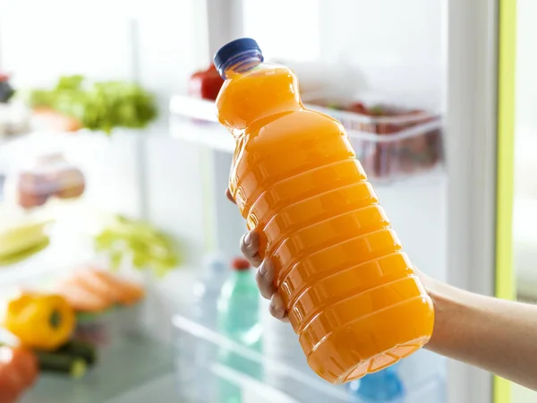 Mujer tomando una botella de jugo de naranja — Foto de Stock