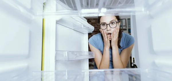 Verzweifelte Frau blickt in ihren leeren Kühlschrank — Stockfoto