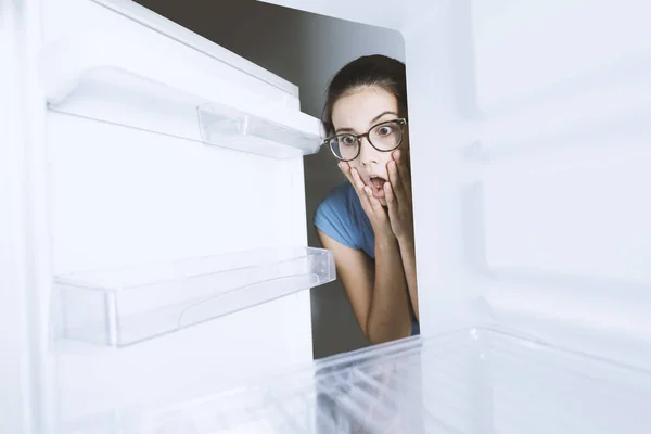 Verzweifelte Frau blickt in ihren leeren Kühlschrank — Stockfoto