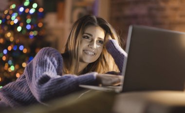 Gülümseyen kadın Noel arifesinde onu laptop ile bağlanma