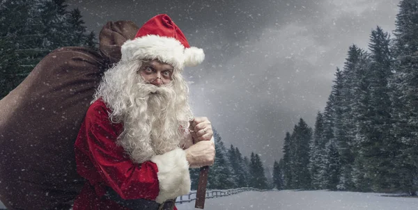 Santa lleva un saco con regalos bajo la nieve — Foto de Stock