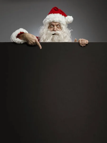 Pai Natal alegre apontando para um sinal de anúncio em branco — Fotografia de Stock
