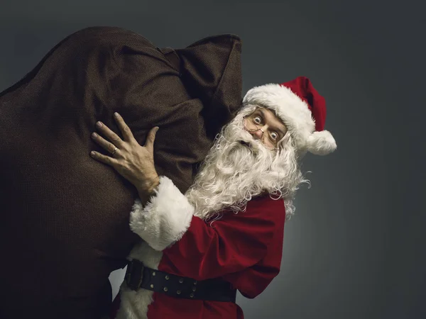 Papai Noel carregando um saco com presentes de Natal — Fotografia de Stock