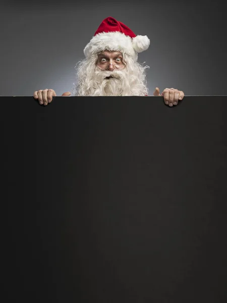 Papai Noel espreitando por trás de um sinal — Fotografia de Stock