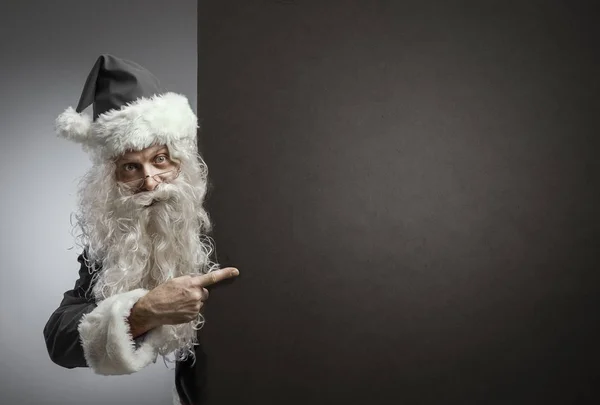 Black Santa Claus pointing at a blank sign