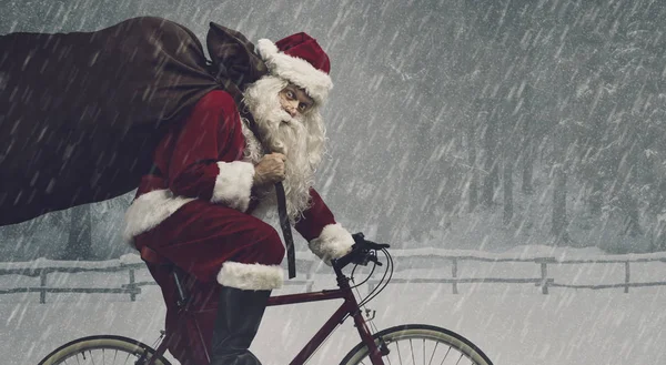 Santa riding a bicycle and carrying gifts — Stock Photo, Image
