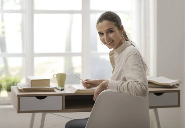 Vrouw thuis studeren en glimlachen — Stockfoto