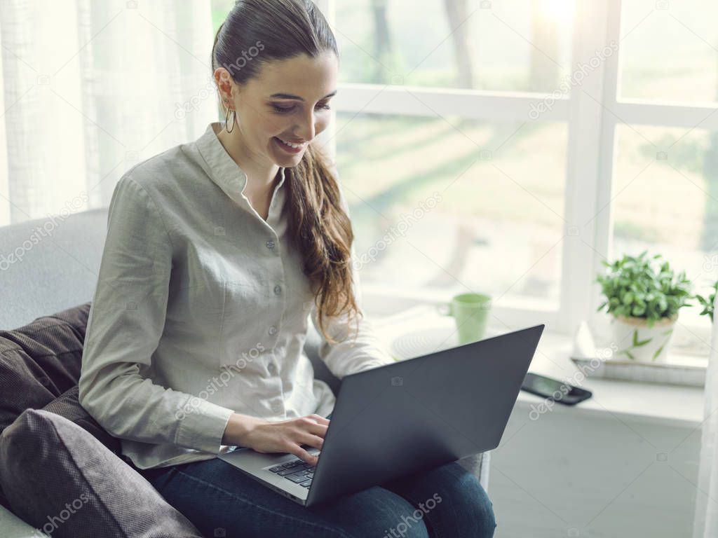 Young woman sitting next to a window and connecting with her lap