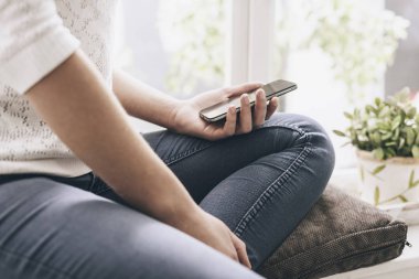 Evde bir akıllı telefon kullanan kadın