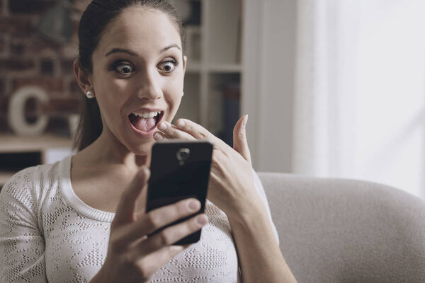 Шокированная женщина соединяется со своим смартфоном
