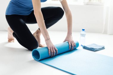 Genç kadın egzersiz sonra onun yoga mat haddeleme