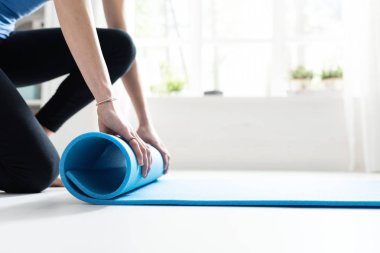 Genç kadın egzersiz sonra onun yoga mat haddeleme