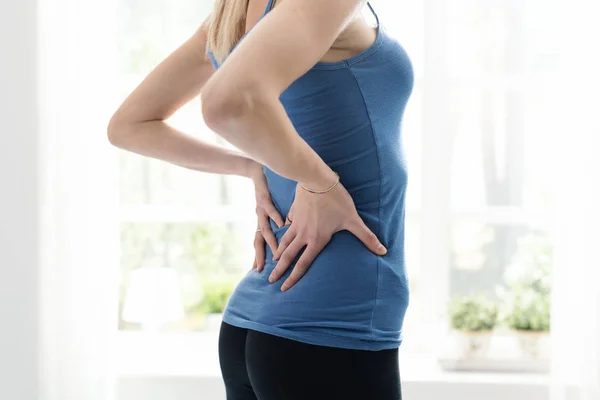 Young woman touching her back — Stock Photo, Image