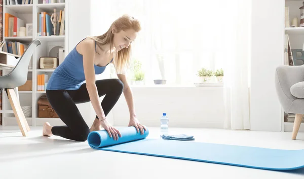 Молодая женщина катит коврик для йоги после тренировки — стоковое фото