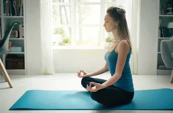 Mujer joven practicando meditación en casa — Foto de Stock