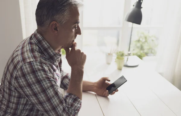 Hombre sosteniendo un teléfono inteligente y esperando una llamada — Foto de Stock