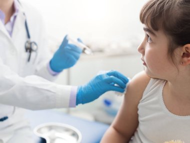 Doktor bir enjeksiyon için korkmuş bir genç kız veriyor