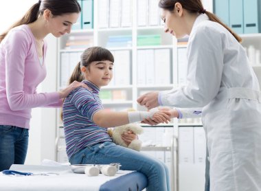 Bir kızın yaralı bilek bir bandaj ile sarma doktor