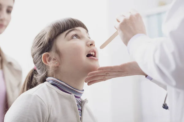 Doktor bir ziyaret sırasında bir kızın boğazını kontrol — Stok fotoğraf