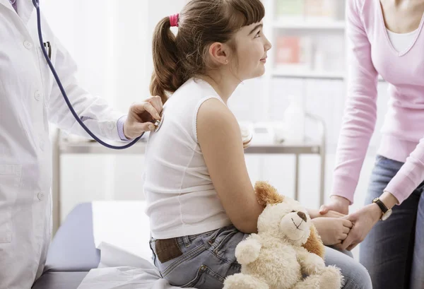 Arts behandeling van een schattige lachende meisje met een stethoscoop — Stockfoto