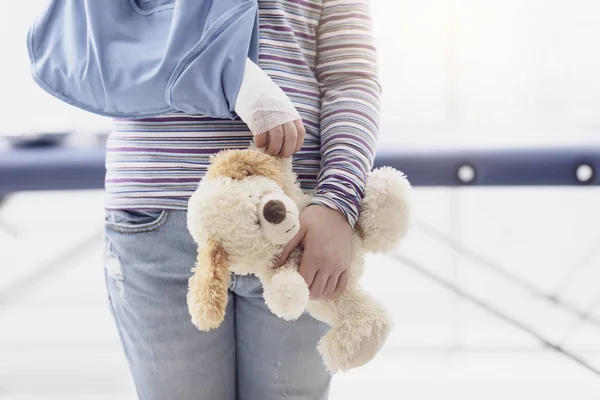 Schattig meisje met arm brace en teddy bear — Stockfoto