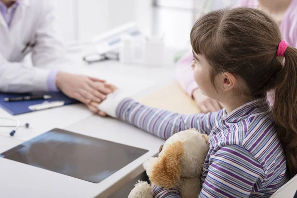 Kinderarts behandeling van een jong meisje met een gewonde pols — Stockfoto