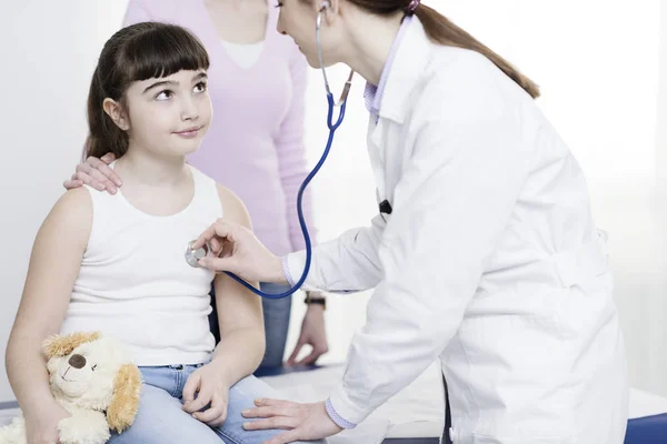 Médecin examinant une jolie fille souriante avec un stéthoscope — Photo