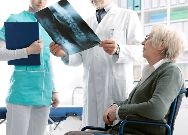 Врач проверяет рентгеновское изображение пожилого пациента — стоковое фото