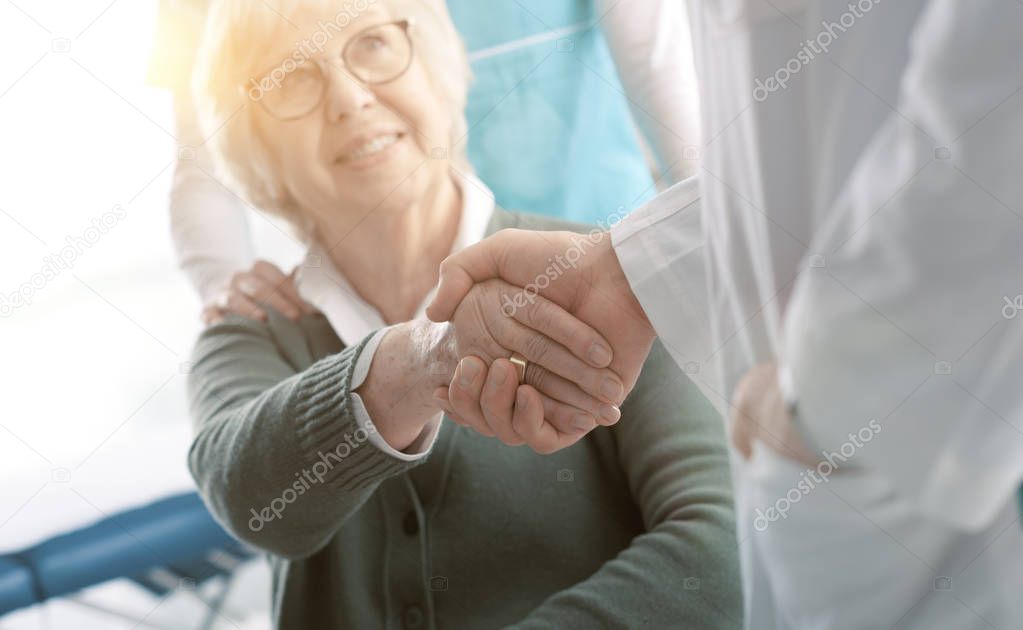 Doctor and senior patient shaking hands in the office