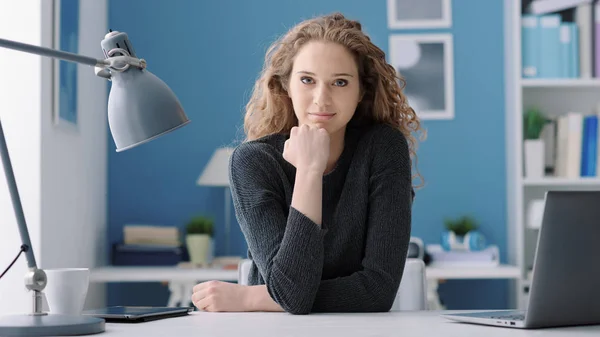 Jeune femme assise au bureau et posant — Photo