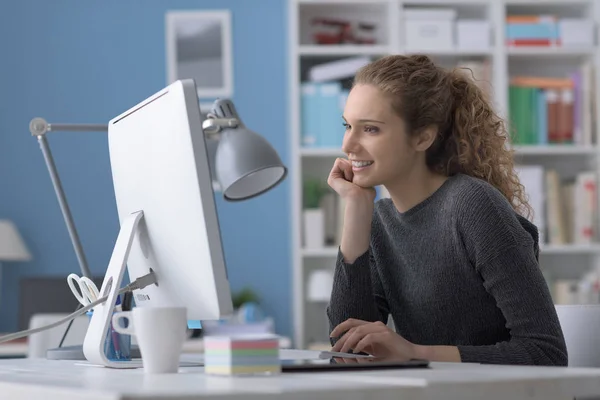 Молодая женщина за компьютером в офисе — стоковое фото